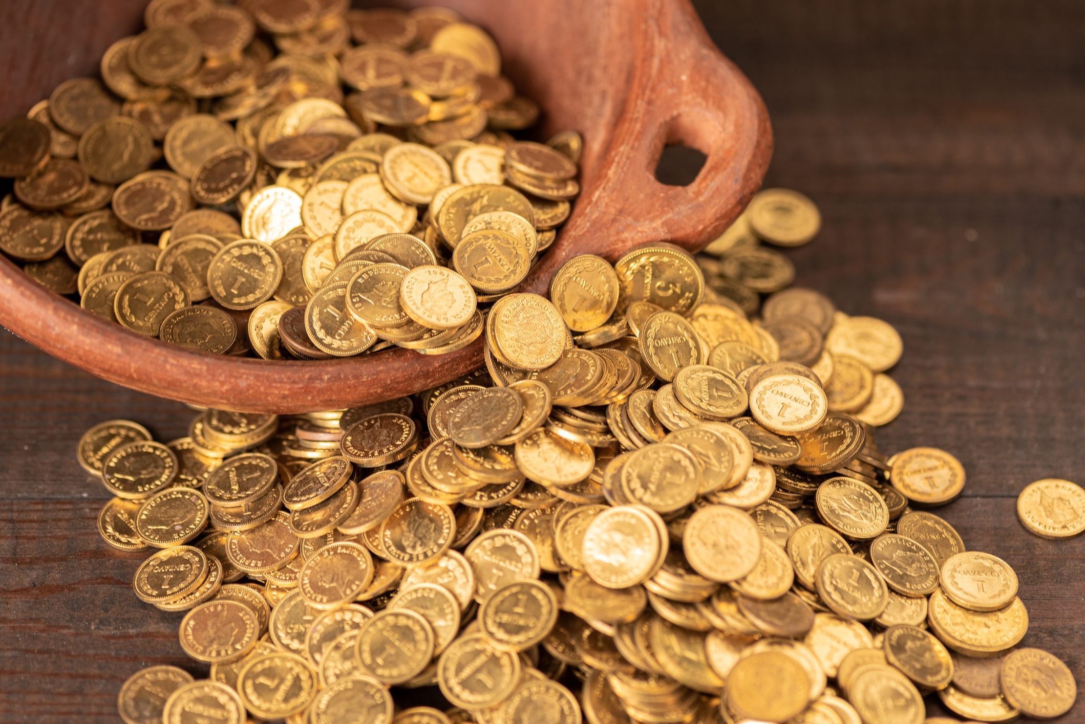 Cascade of small golden coins from a terracotta pot