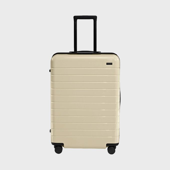 A beige rolling suitcase stands upright against a plain white background.