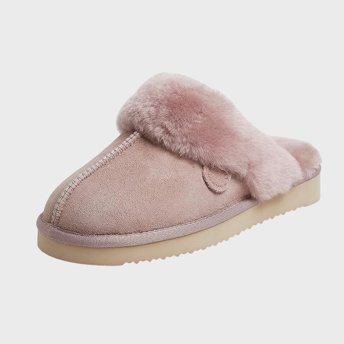 A fluffy pink slipper rests on a plain background, featuring a soft fur lining and beige sole.