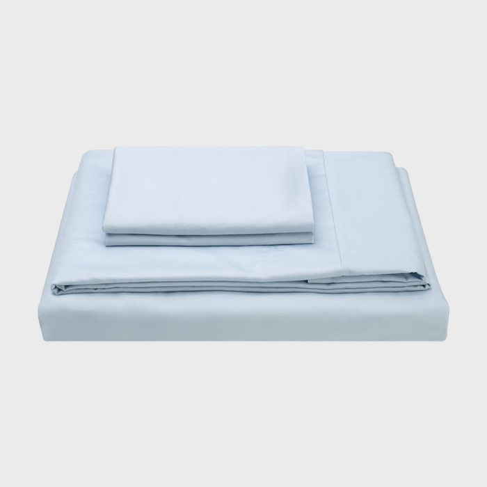 A stack of light blue bed sheets sits neatly folded on a plain white surface.
