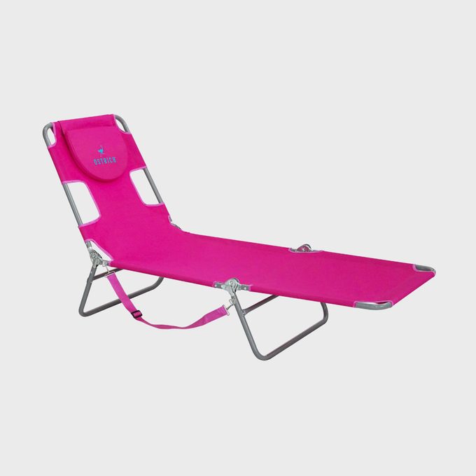 Pink folding lounge chair sits unfolded, featuring a headrest and metal frame. 
