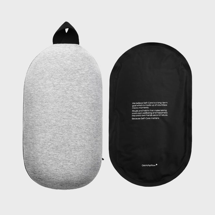 Gray pillow lies next to a black fabric case with motivational text about self-care, set against a plain background.