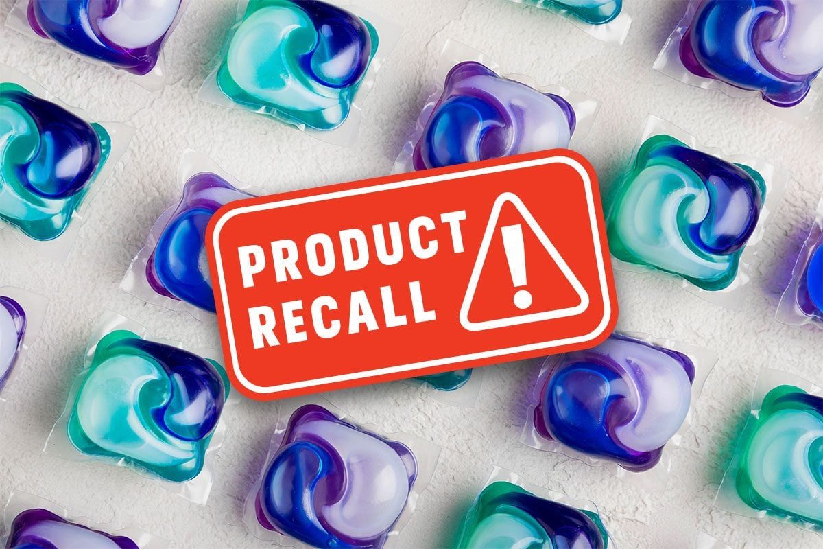 Laundry pods displayed beneath a red sign reading "PRODUCT RECALL!" on a textured white surface.