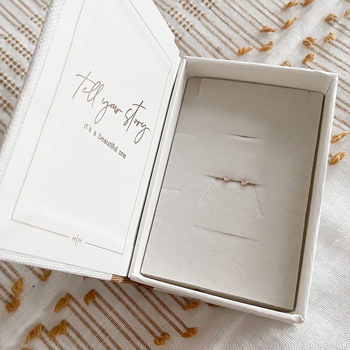 Stud earrings rest in a jewelry box with text reading, 