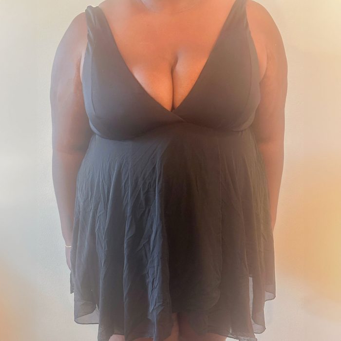 Dress drapes gracefully; worn by a standing person against a softly lit, plain backdrop.