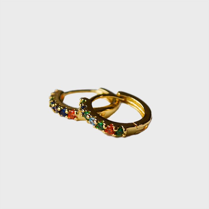 Gold hoop earrings adorned with multicolored gemstones are resting on a plain white background.