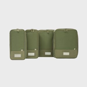 Four green packing cubes are upright, displaying various sizes, each with handle and label slot, against a plain white background.