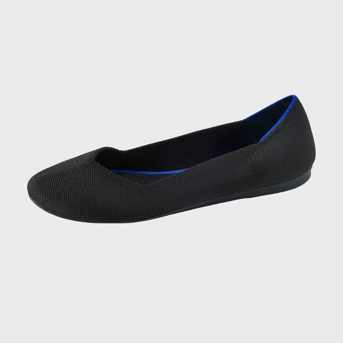 A black ballet flat with a blue inner lining is displayed against a plain white background.