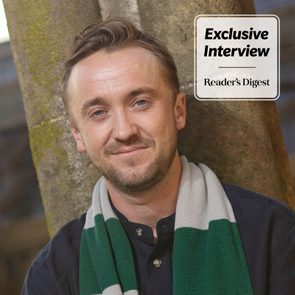 Person leans against mossy tree, smiling, wearing striped scarf; text reads 