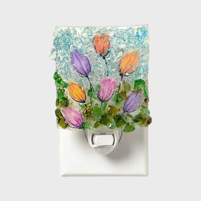 A decorative nightlight, featuring colorful flower artwork, is set within a textured glass cover, mounted on a white wall plate.