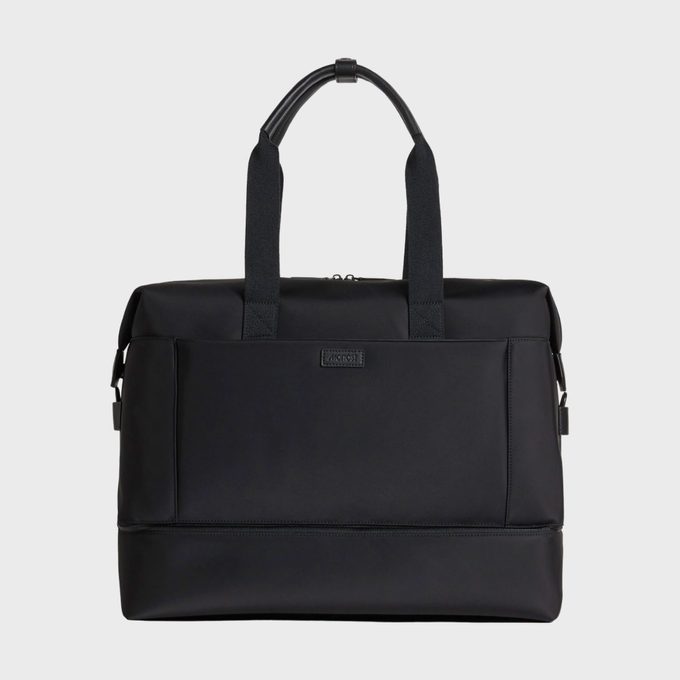 Black duffel bag sits, featuring sturdy handles and a sleek rectangular shape, set against a plain white background.