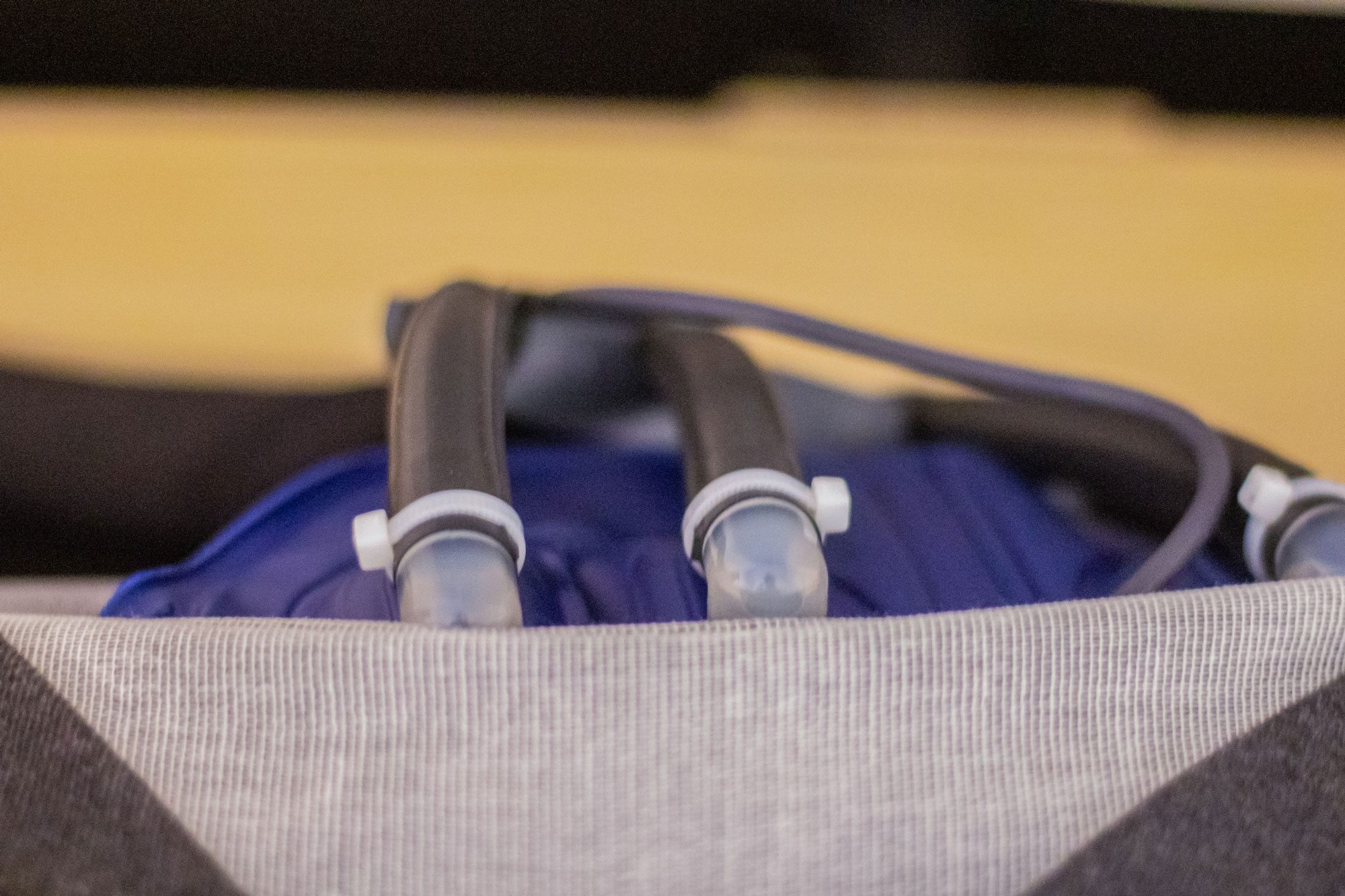 Black water tubes extend from a blue hydration backpack, resting on a gray surface.