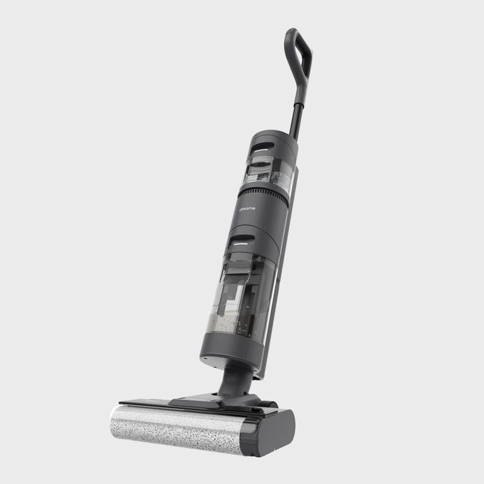 Vacuum cleaner stands upright, showcasing a sleek design and transparent compartments, set against a plain gray background.
