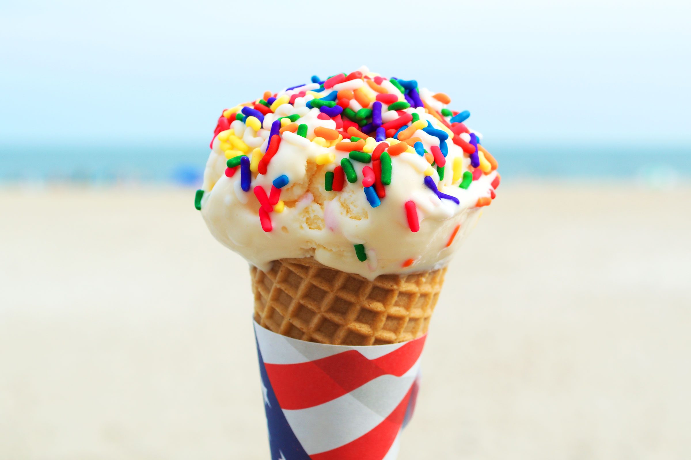 vanilla ice cream cone with rainbow sprinkles on the beach