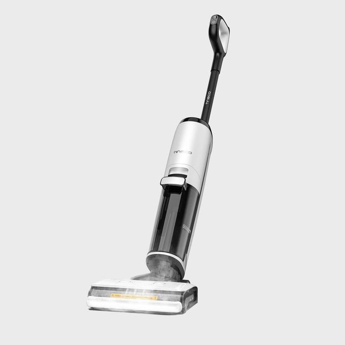 Vacuum cleaner stands on a light gray background, displaying a sleek, modern design with a long handle and visible front section.