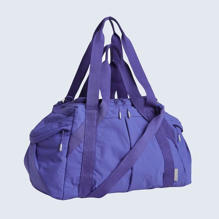 Purple duffel bag rests with straps hanging down, displayed against a plain light background.
