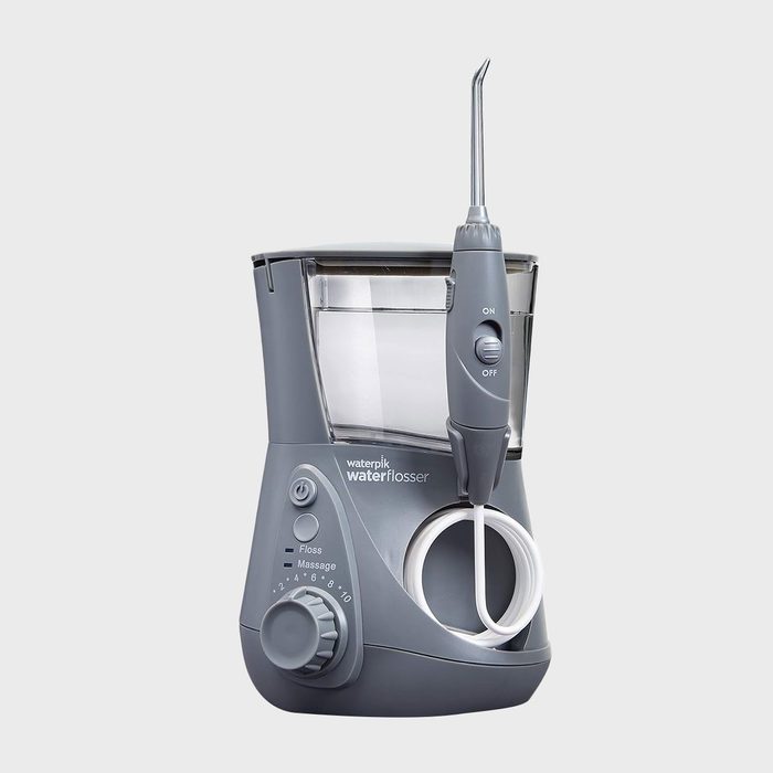 Water flosser stands on a surface with a detachable handle. Gray with dials and labeled 