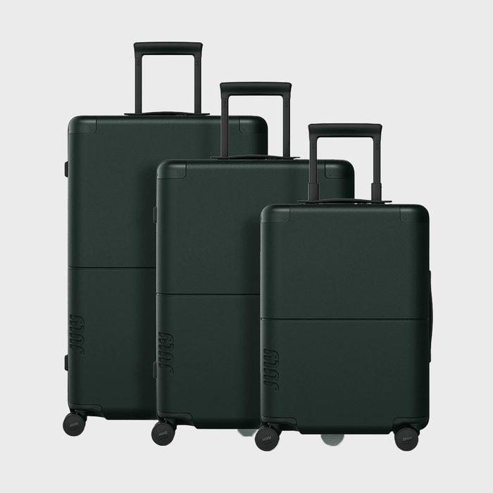 Three dark green suitcases stand upright, featuring extended handles and wheels, arranged in ascending size order against a plain gray background.