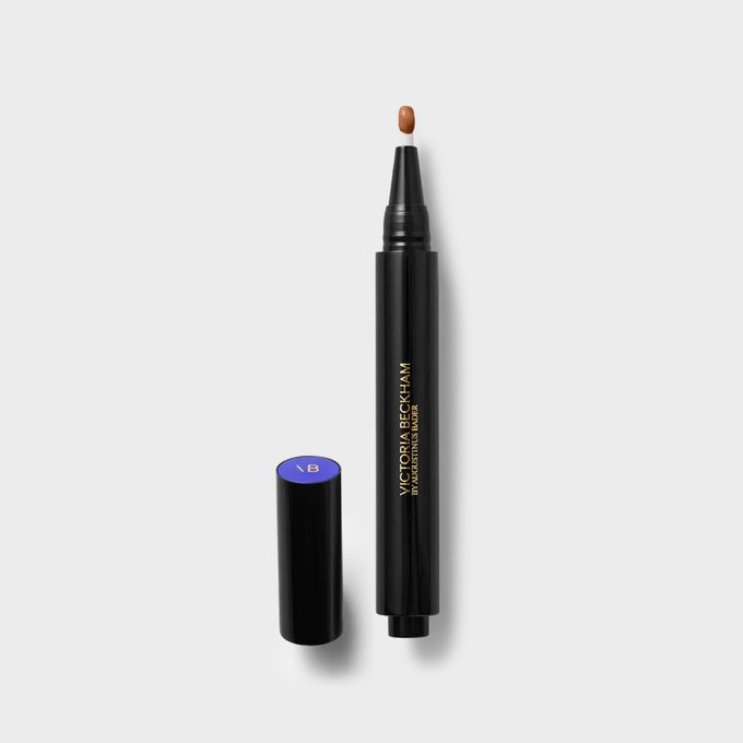 Black cosmetic pen dispenses brown liquid on a white surface; its cap lays beside it. Text reads 