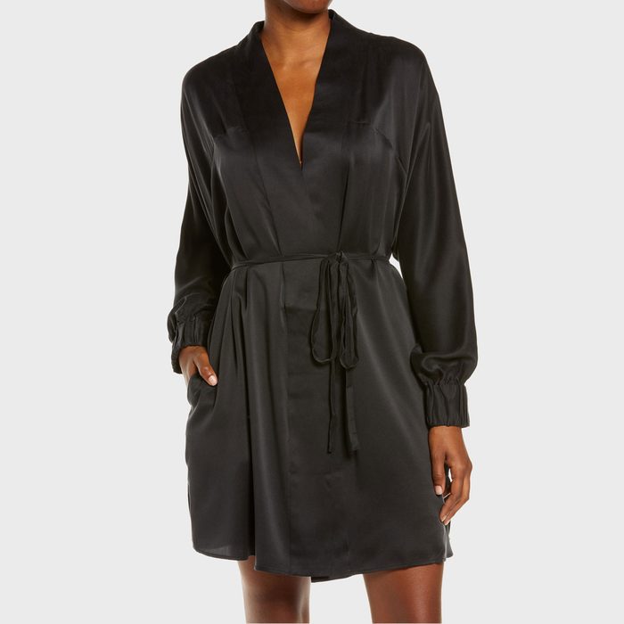 A person wears a silky black robe tied at the waist, standing against a plain white background.
