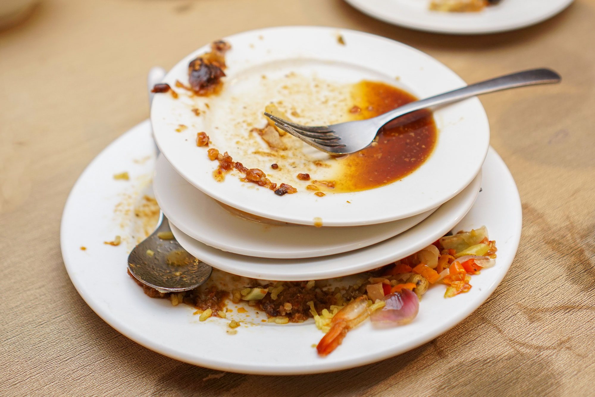 Stack Of Dirty Plates With Leftover Food On Table
