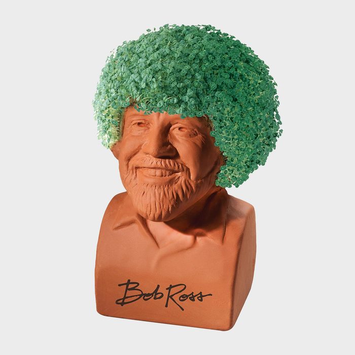 Bust with green foliage hair sits against a plain background. Signature reads 