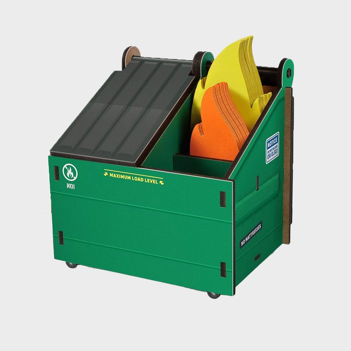 A miniature green dumpster contains colorful foam flames, resembling fire, set against a plain background. Text reads 