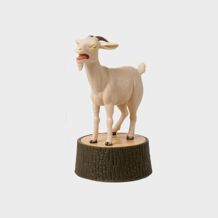 A goat figurine stands on a textured tree stump base against a plain background.