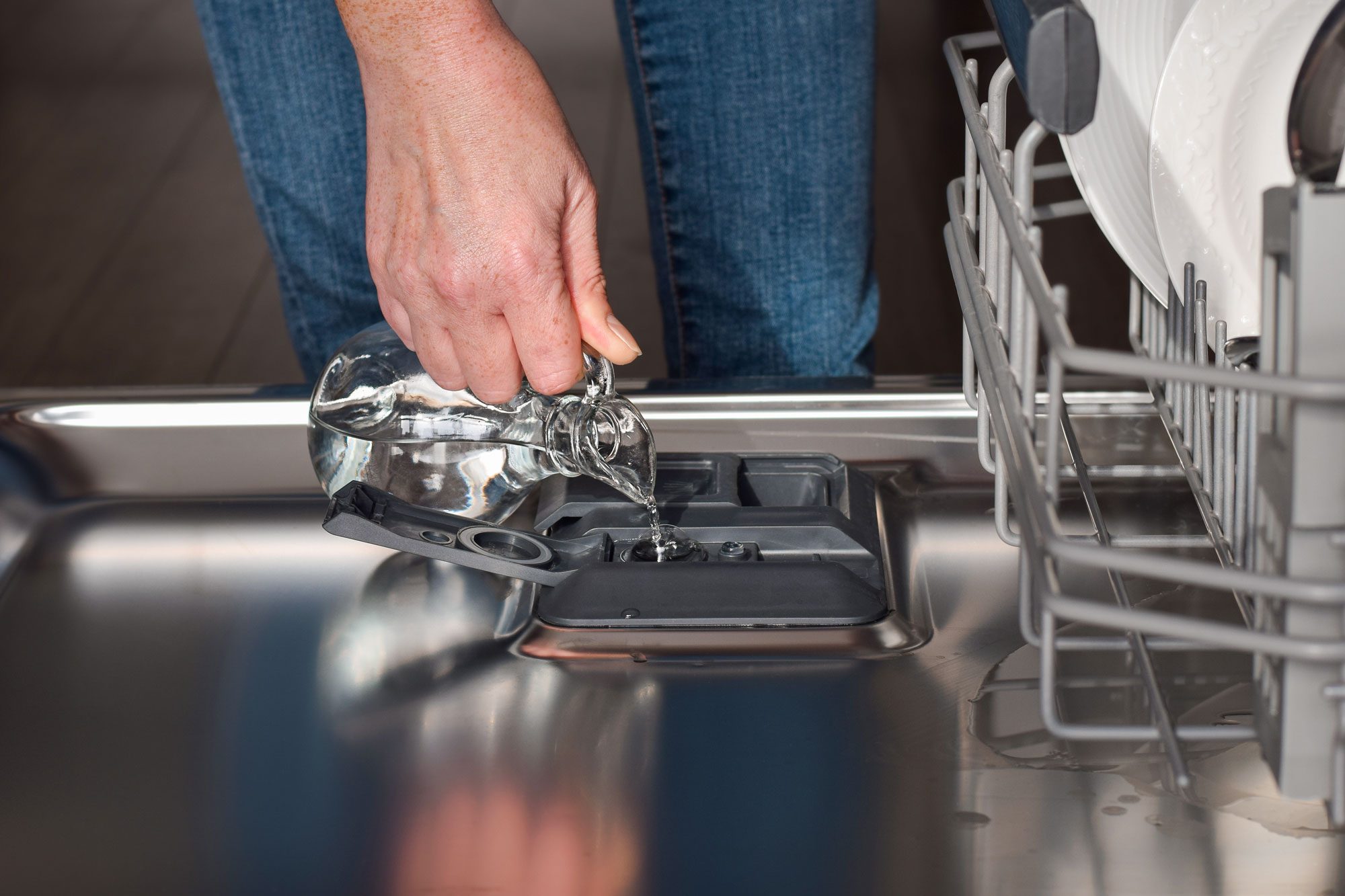 Woman Filling Up Dishwasher Rinse Aid Dispenser With Vinegar