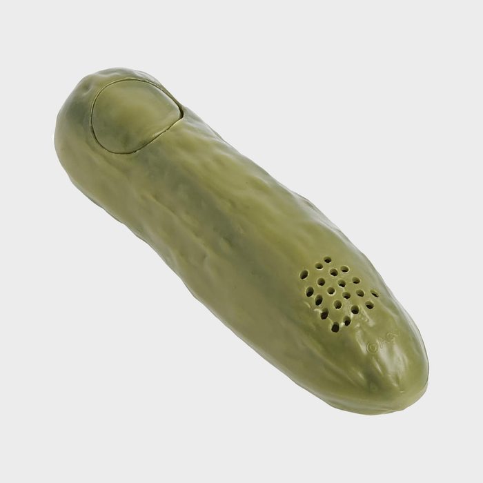 Pickle-shaped object with speaker holes, resting on a plain surface.