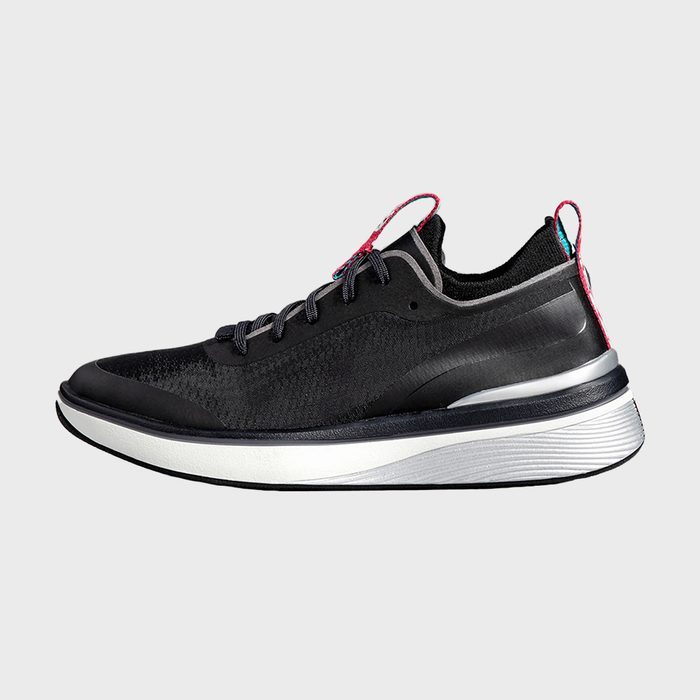 A black athletic shoe with red accents and a thick, white sole on a plain gray background.