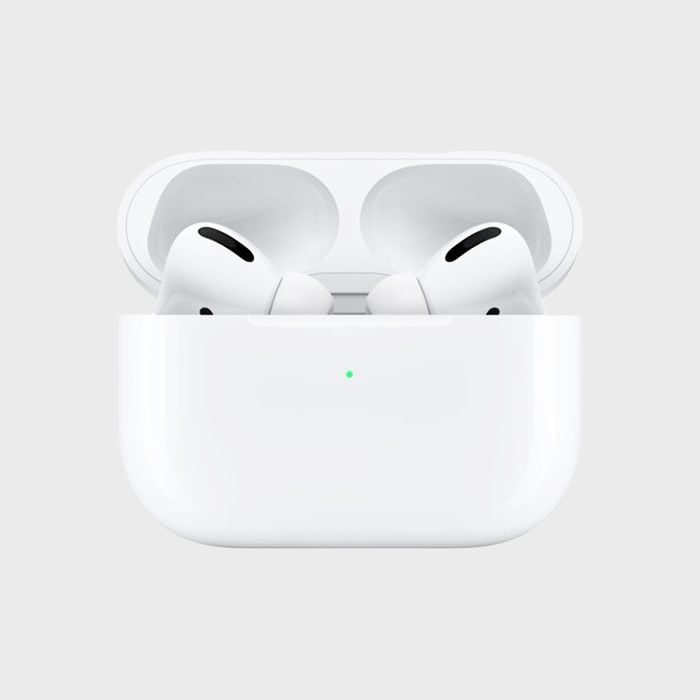 White wireless earbuds resting in an open charging case with a small green light, set against a plain gray background.
