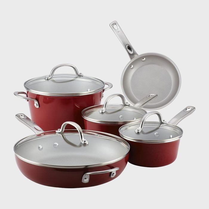 Cookware set stacked together; includes pots and pans with red exterior, silver handles, and glass lids, displayed against a plain gray background.