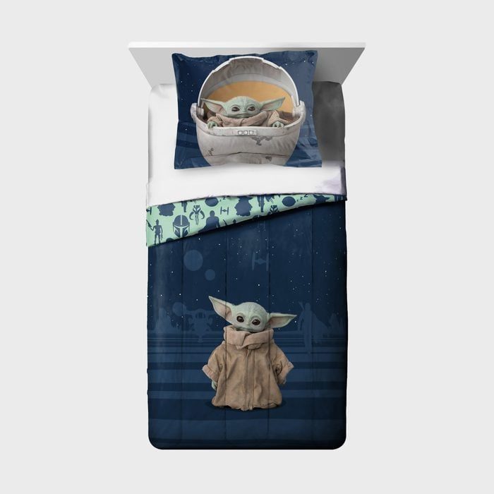 Bedding set features cartoon character with large ears, printed on pillow and blanket, amidst starry space-themed patterns and silhouettes of various figures.