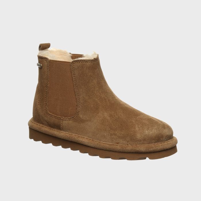 Brown suede boot sits upright, showcasing elastic sides and white fleece interior, on a light grey background.