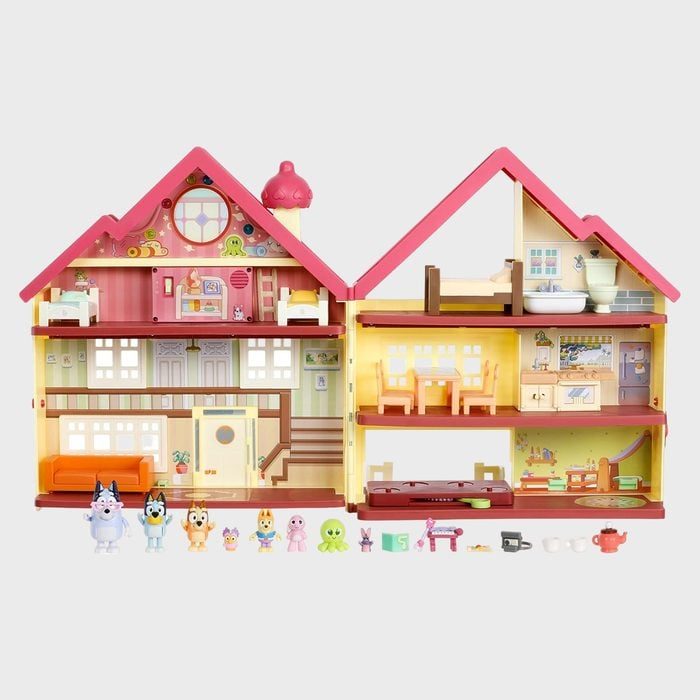 Dollhouse showcases colorful interior rooms with miniature furniture. Figures and small accessories are arranged outside, enhancing playtime in a vibrant, imaginative setting.