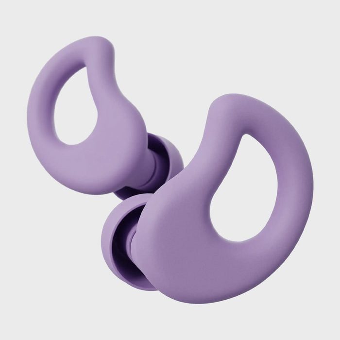 Purple earplugs are lying side by side against a light gray background, featuring ergonomic hooks designed for a secure fit in the ear.