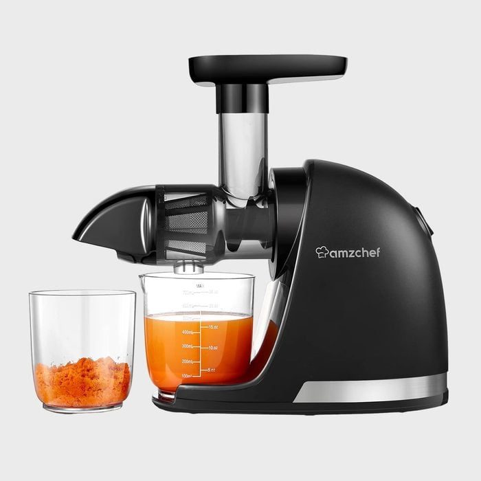 Juicer extracting orange liquid into glass, with pulp collected in separate container. Set against a plain gray background. 