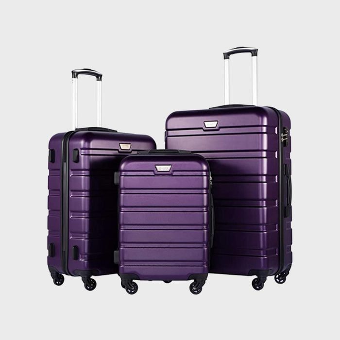 Three purple suitcases stand with extended handles, featuring four wheels each, positioned against a plain background.
