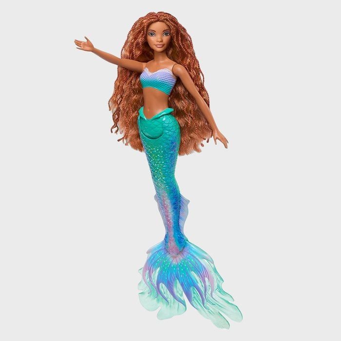 A mermaid doll extends one arm, showcasing a colorful tail and long wavy hair against a plain background.