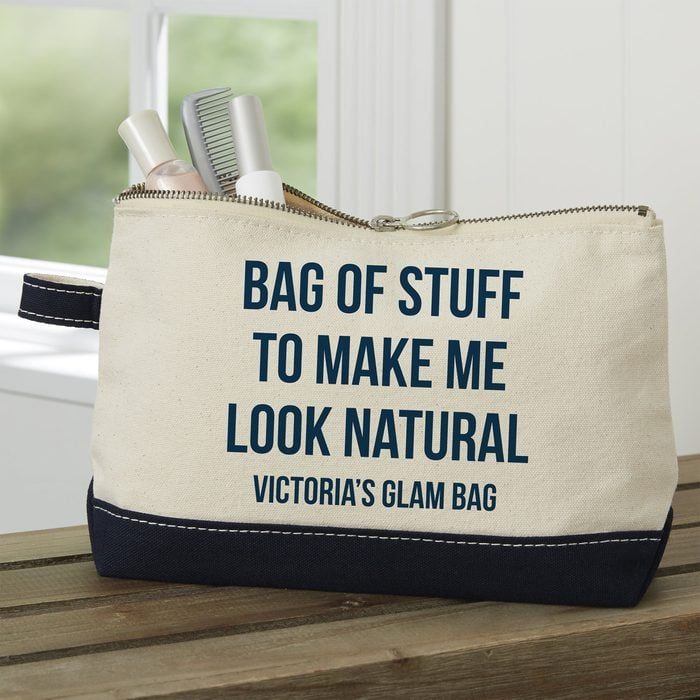 Bag holds makeup and toiletries, sitting on a wooden surface; text reads â€œBag Of Stuff To Make Me Look Natural, Victoria's Glam Bag.â€