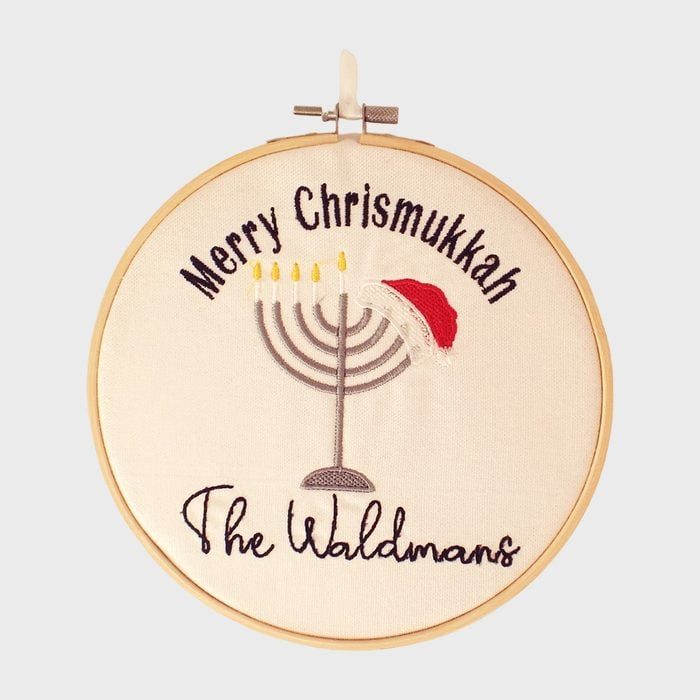 Embroidery hoop displays menorah with Santa hat, surrounded by 
