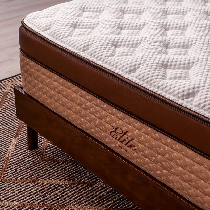 Mattress rests on a wooden bed frame, adorned with textured fabric and 
