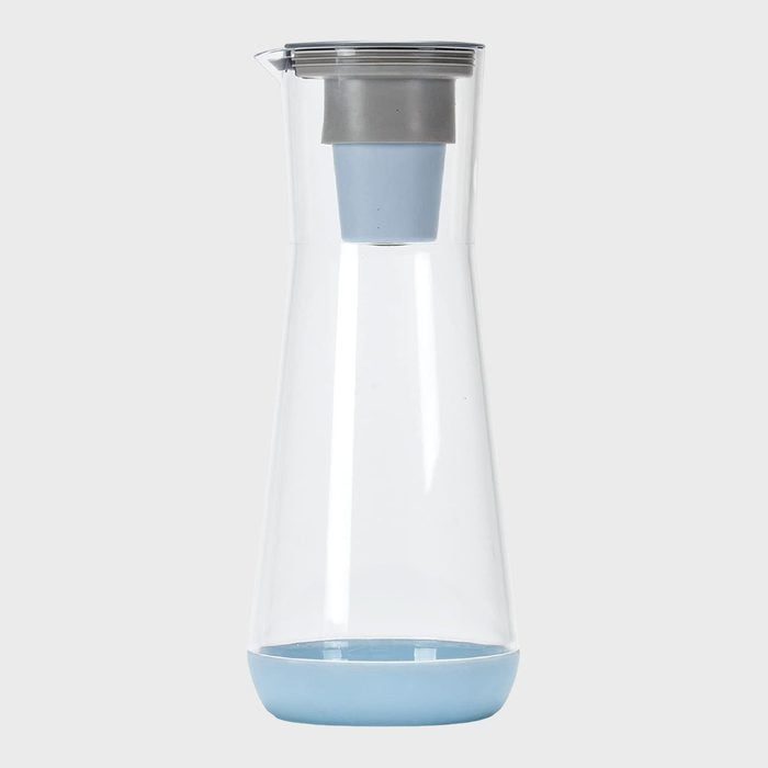 A clear pitcher holds a blue filter, standing upright on a plain gray background.