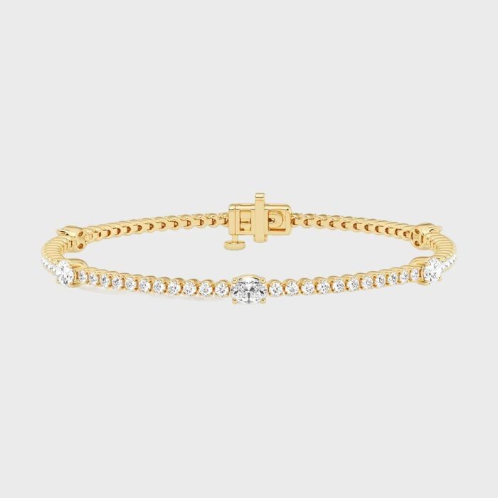 Gold bracelet with small diamonds encircles it, featuring a central, larger diamond on a plain background.