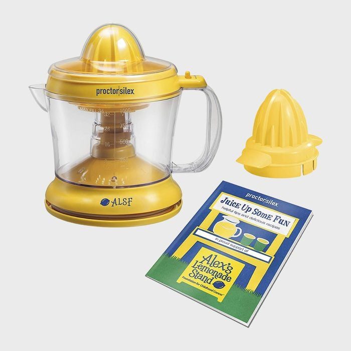 Juicer rests on a surface with a measuring container and citrus reamer, accompanied by a booklet titled 