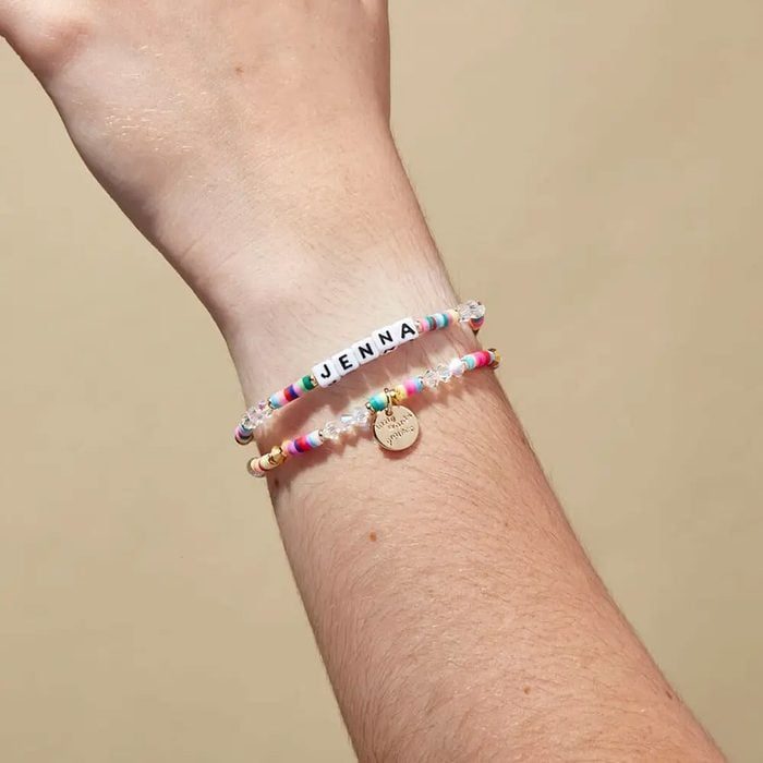 Bracelets rest on a wrist, featuring colorful beads. One spell 