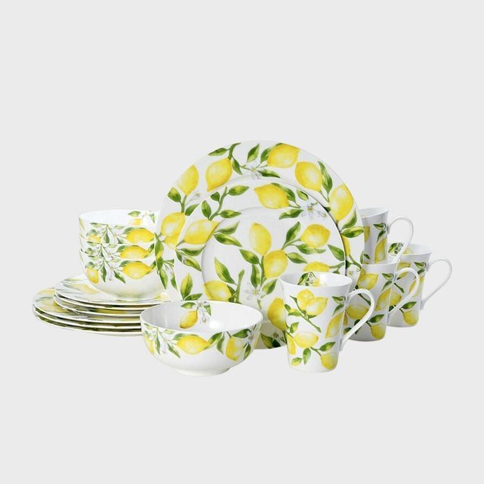 Dinnerware set features lemons and leaves, including plates, bowls, and mugs, arranged neatly on a plain background.