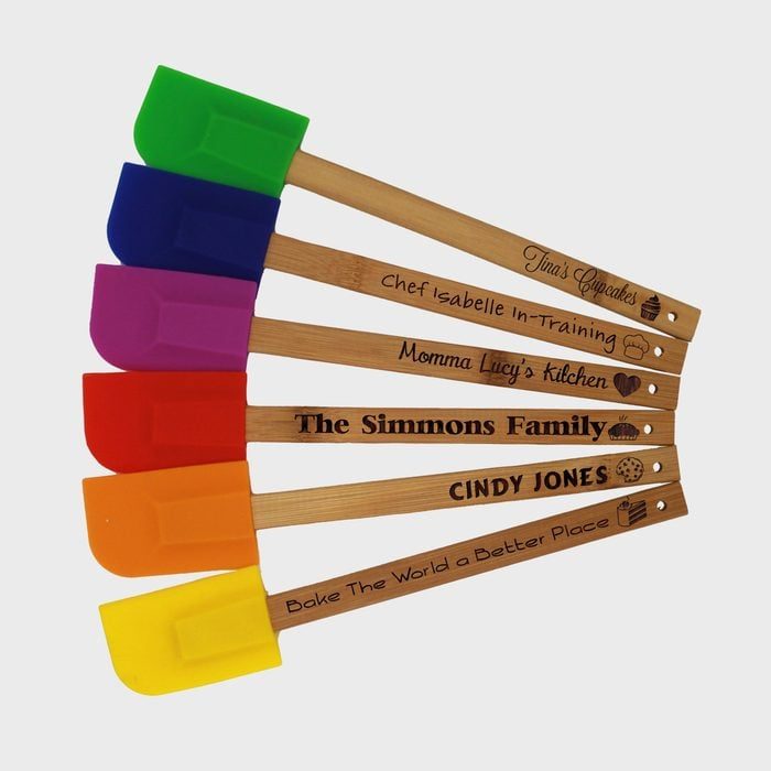 Colourful silicone spatulas with engraved wooden handles display text like 