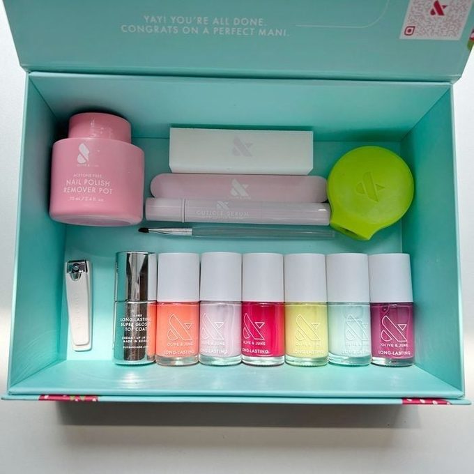 Nail care kit displayed in an open box includes polishes, remover, buffer, and a nail clipper within a pastel-colored interior. Text: 
